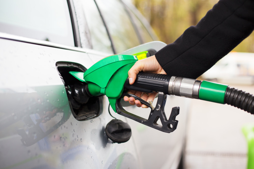 Hand holding fuel pump and refilling car at petrol station